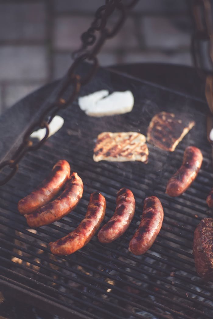 Delicious sausages and steak grilling over an outdoor barbecue with a smoky, chargrilled finish, perfect for a summer cookout.