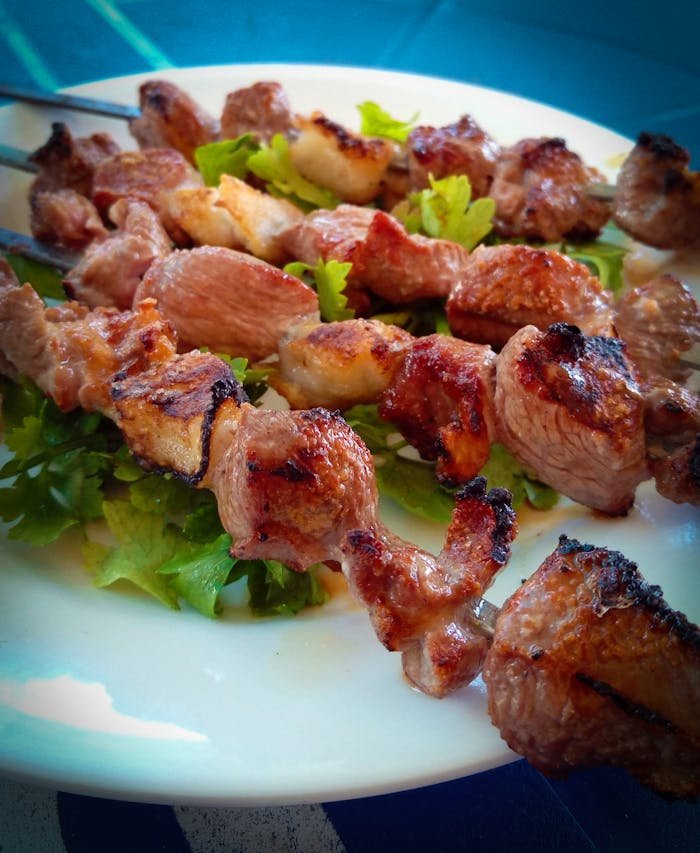 Delicious grilled meat skewers on a bed of fresh greens, perfect for a barbecue meal.